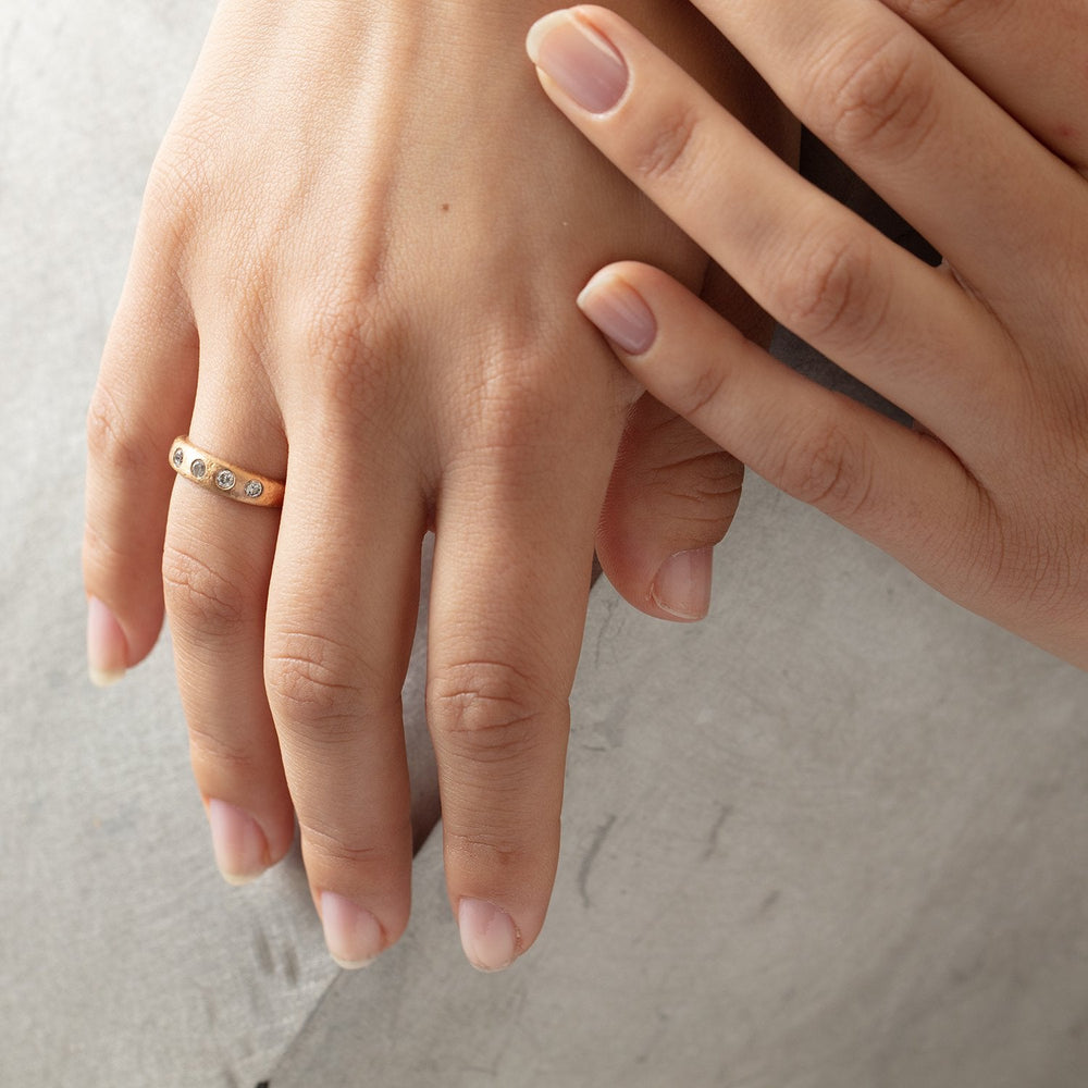 
                      
                        Narrow Molten Band in 18k rose gold with diamonds by Betsy Barron, worn on model's right hand.
                      
                    