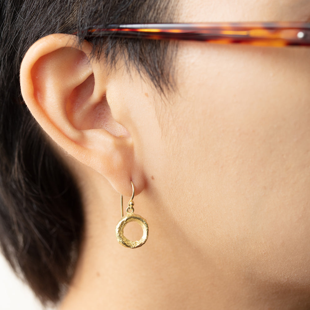 Model wearing 18k yellow gold Organic Donut Earring in right ear